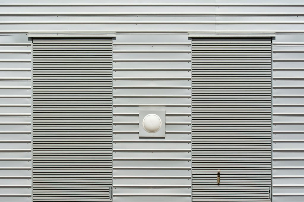 Close-up of a modern industrial building with metal siding and roller doors.